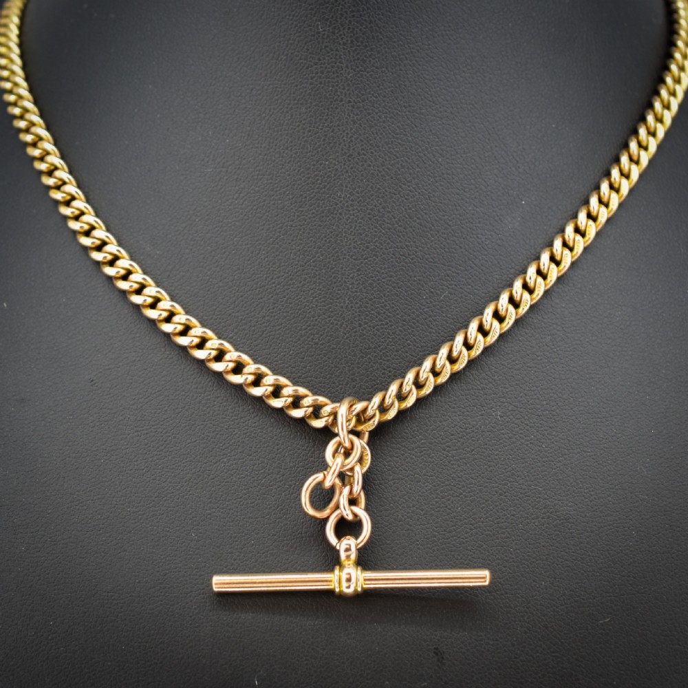A 9ct yellow gold uniform curb link Albert watch chain featuring a T-bar and dog clip fastings. View II