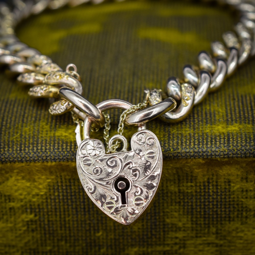 A 9ct yellow gold curb link chain bracelet featuring alternating plain and hand-engraved links, fitted with an engraved heart-shaped padlock clasp and safety chain. View II