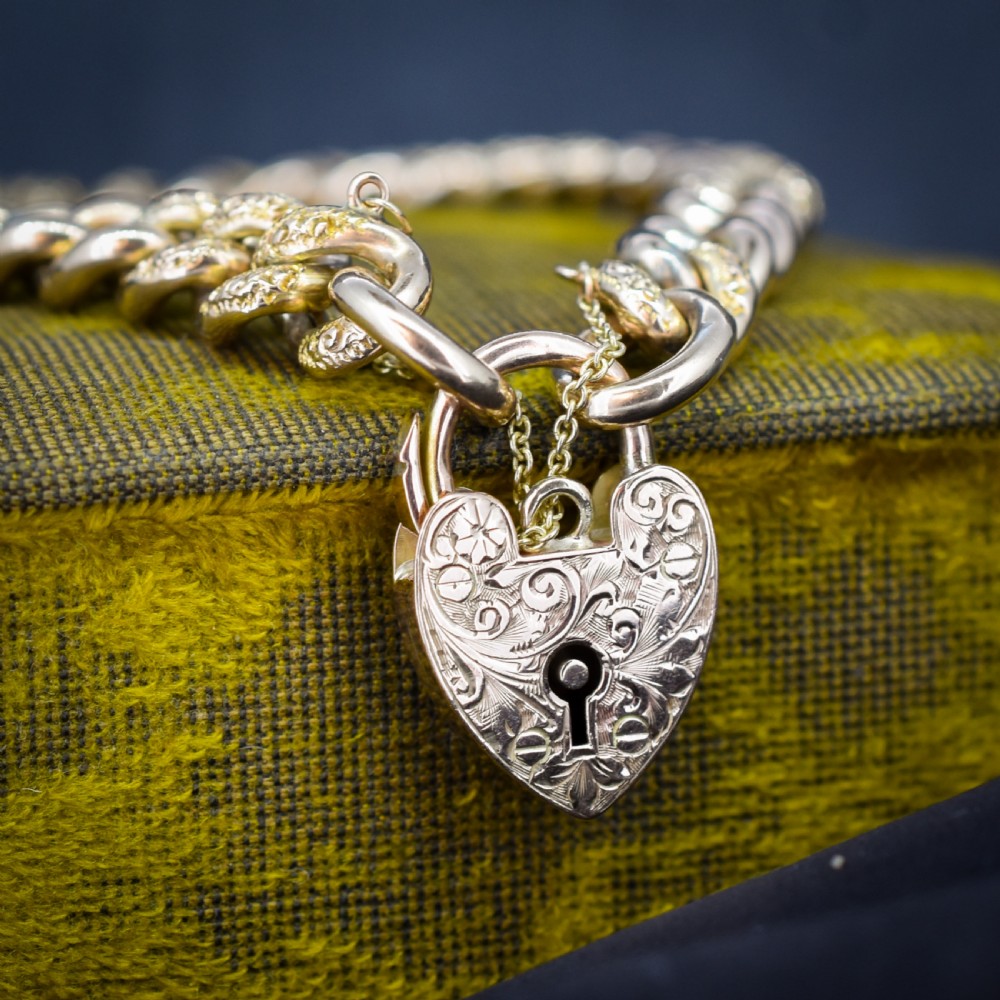 A 9ct yellow gold curb link chain bracelet featuring alternating plain and hand-engraved links, fitted with an engraved heart-shaped padlock clasp and safety chain. View III
