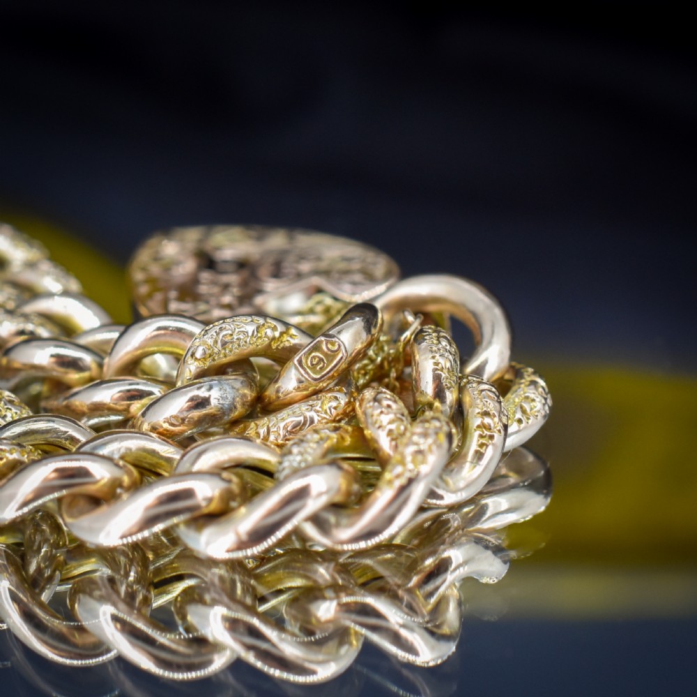 A 9ct yellow gold curb link chain bracelet featuring alternating plain and hand-engraved links, fitted with an engraved heart-shaped padlock clasp and safety chain. View VI