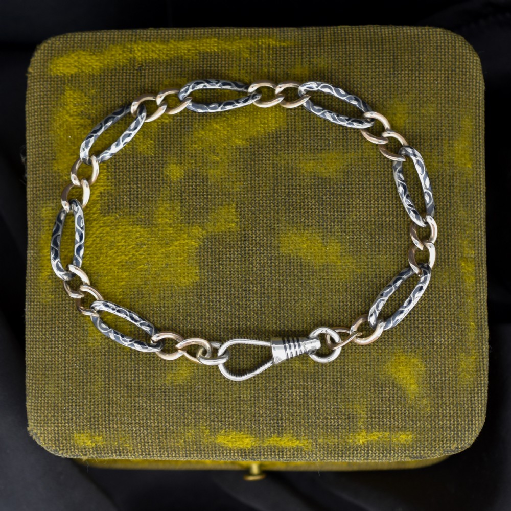 An antique chain bracelet consisting of patterned niello silver links connected by smooth gold links and secured with a swivel dog clip clasp. View II