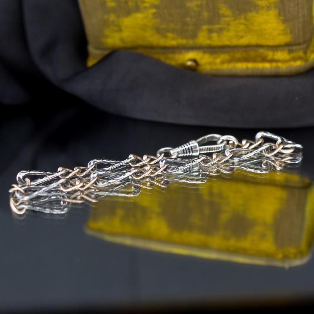 An antique chain bracelet consisting of patterned niello silver links connected by smooth gold links and secured with a swivel dog clip clasp. View V