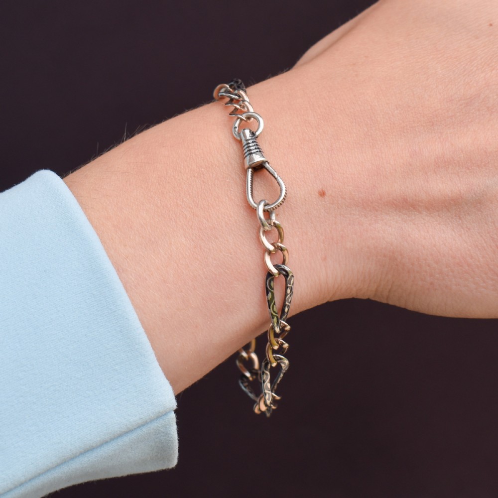 An antique chain bracelet consisting of patterned niello silver links connected by smooth gold links and secured with a swivel dog clip clasp. View VII