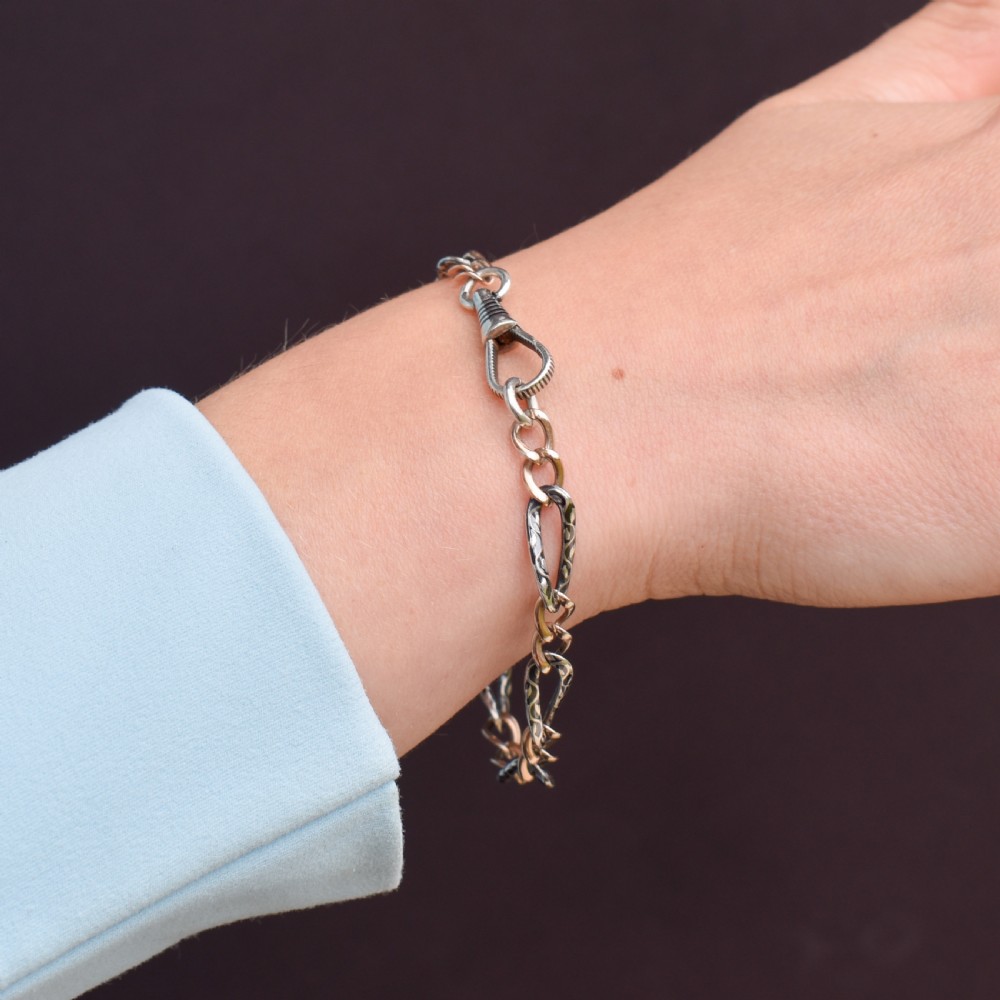 An antique chain bracelet consisting of patterned niello silver links connected by smooth gold links and secured with a swivel dog clip clasp. View VIII