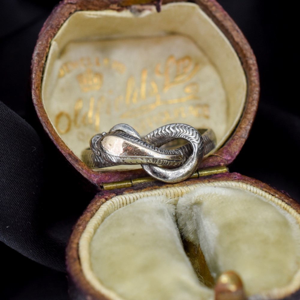 An antique silver ring crafted in the form of a coiled serpent with detailed scale engraving.