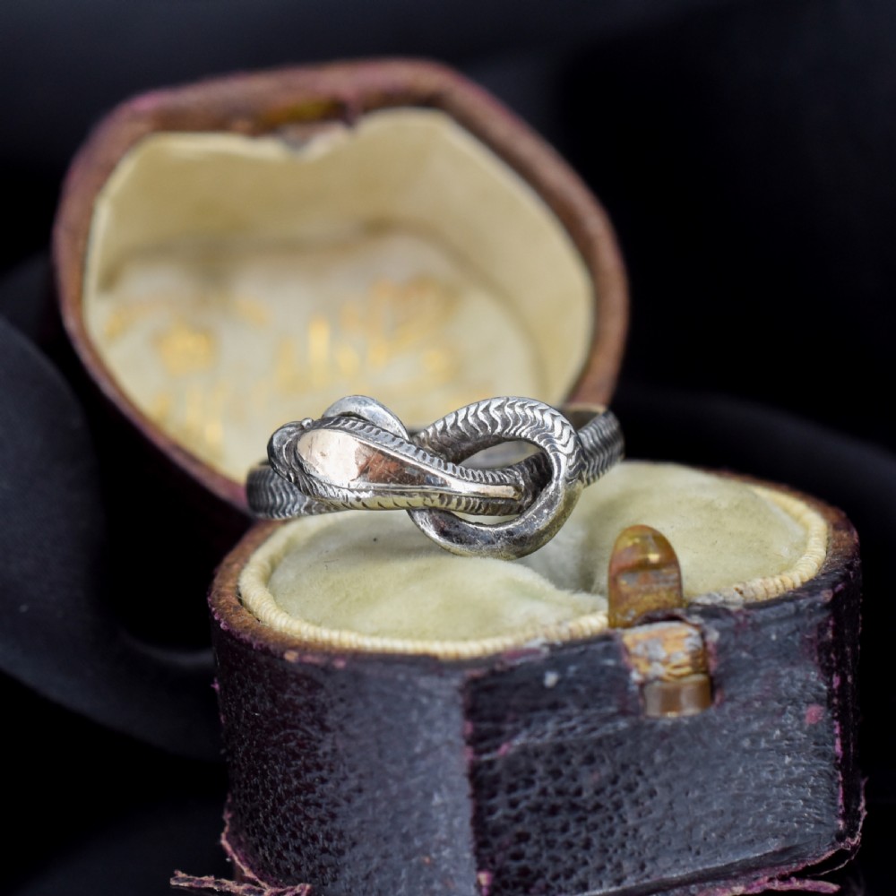 An antique silver ring crafted in the form of a coiled serpent with detailed scale engraving. View II
