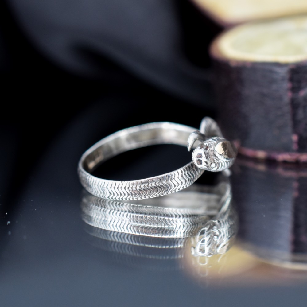 An antique silver ring crafted in the form of a coiled serpent with detailed scale engraving. View IV