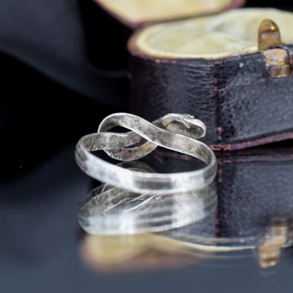 An antique silver ring crafted in the form of a coiled serpent with detailed scale engraving. View V