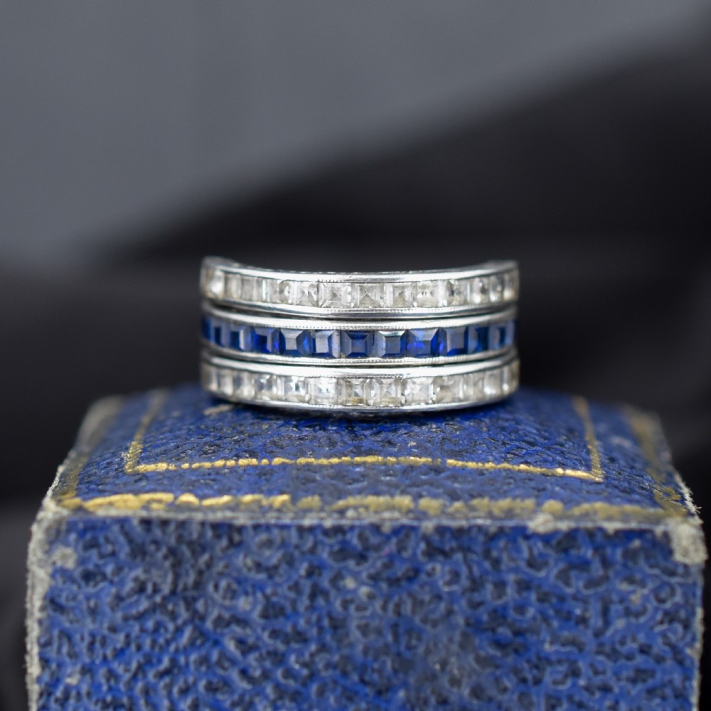 An Art Deco sterling silver swivel eternity ring featuring a central band of channel-set red paste stones flanked by hinged swivelling bands of clear paste stones. View II