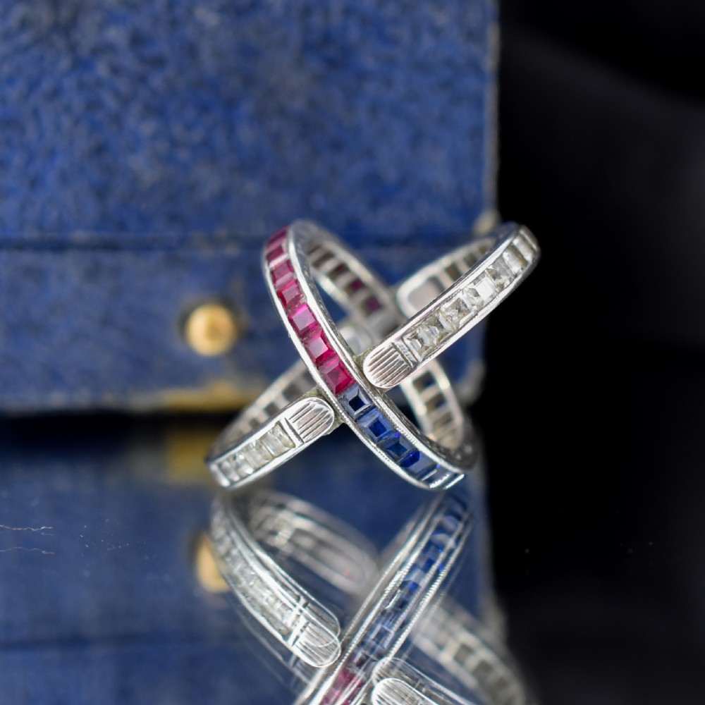 An Art Deco sterling silver swivel eternity ring featuring a central band of channel-set red paste stones flanked by hinged swivelling bands of clear paste stones. View III