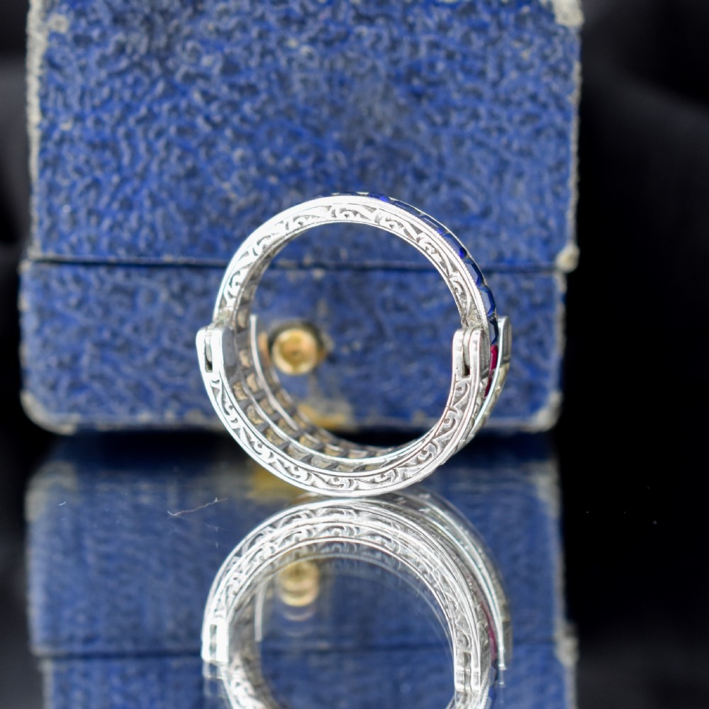 An Art Deco sterling silver swivel eternity ring featuring a central band of channel-set red paste stones flanked by hinged swivelling bands of clear paste stones. View V
