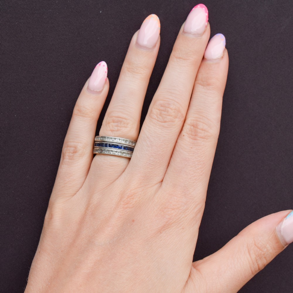 An Art Deco sterling silver swivel eternity ring featuring a central band of channel-set red paste stones flanked by hinged swivelling bands of clear paste stones. View IX