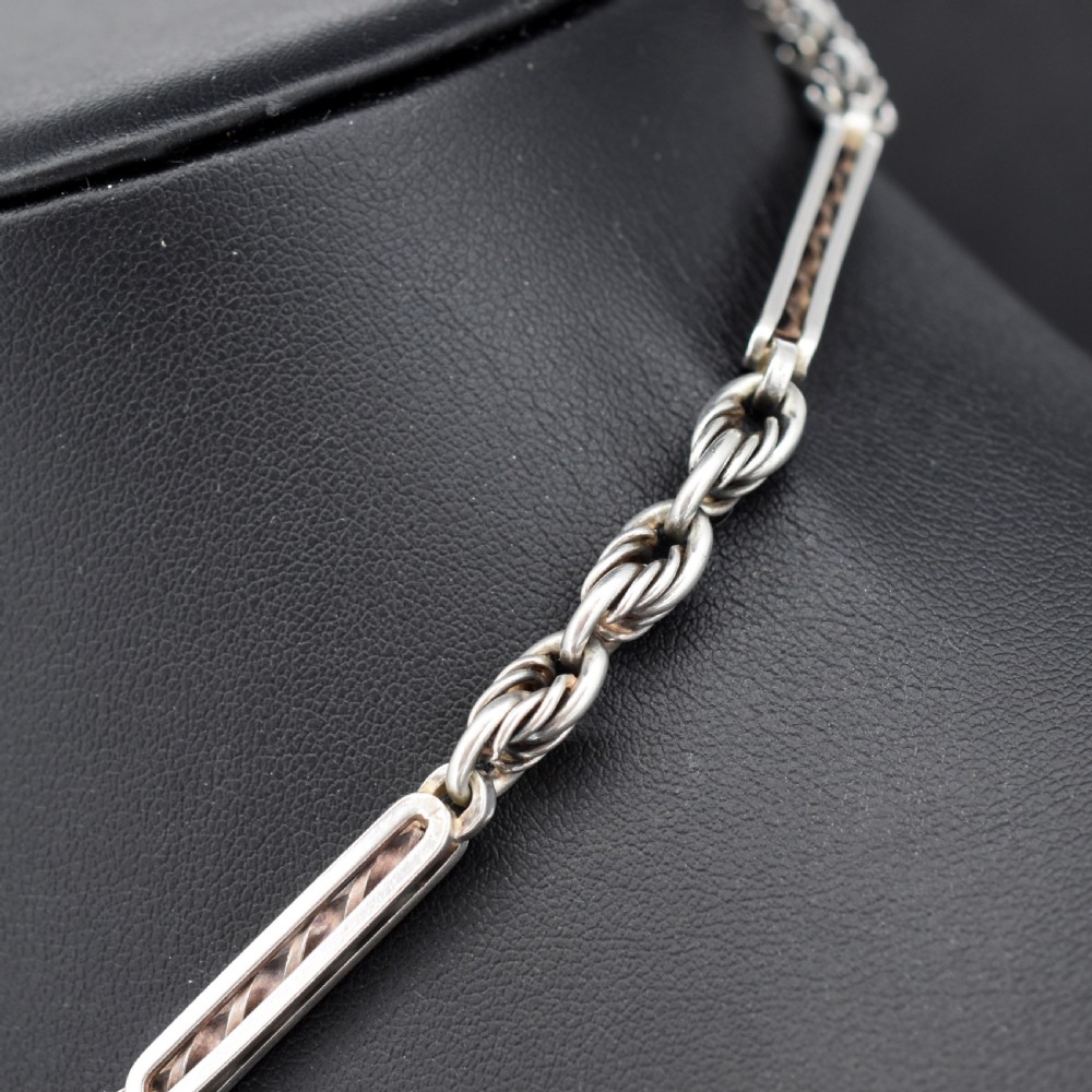 An antique sterling silver Albert chain necklace featuring elongated bar links, twisted rope sections, a T-bar attachment, and a swivel clasp. View VI