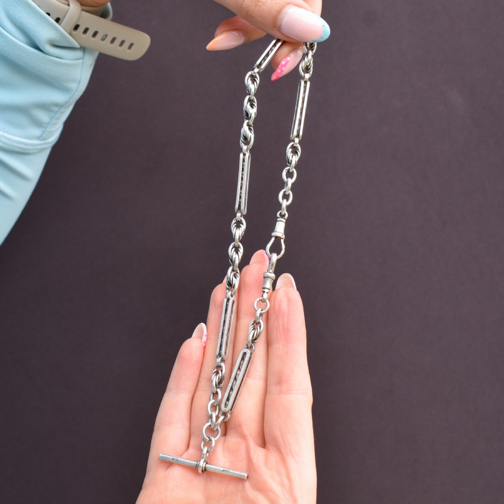 An antique sterling silver Albert chain necklace featuring elongated bar links, twisted rope sections, a T-bar attachment, and a swivel clasp. View IX