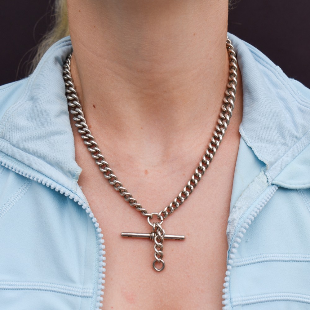 A sterling silver curb link Albert watch chain featuring a T-bar attachment and a swivel clip. View IX