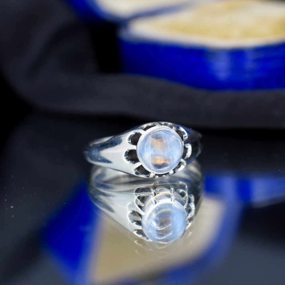 An antique sterling silver ring featuring a smooth oval moonstone cabochon held within pierced, decorative silver shoulders. View III
