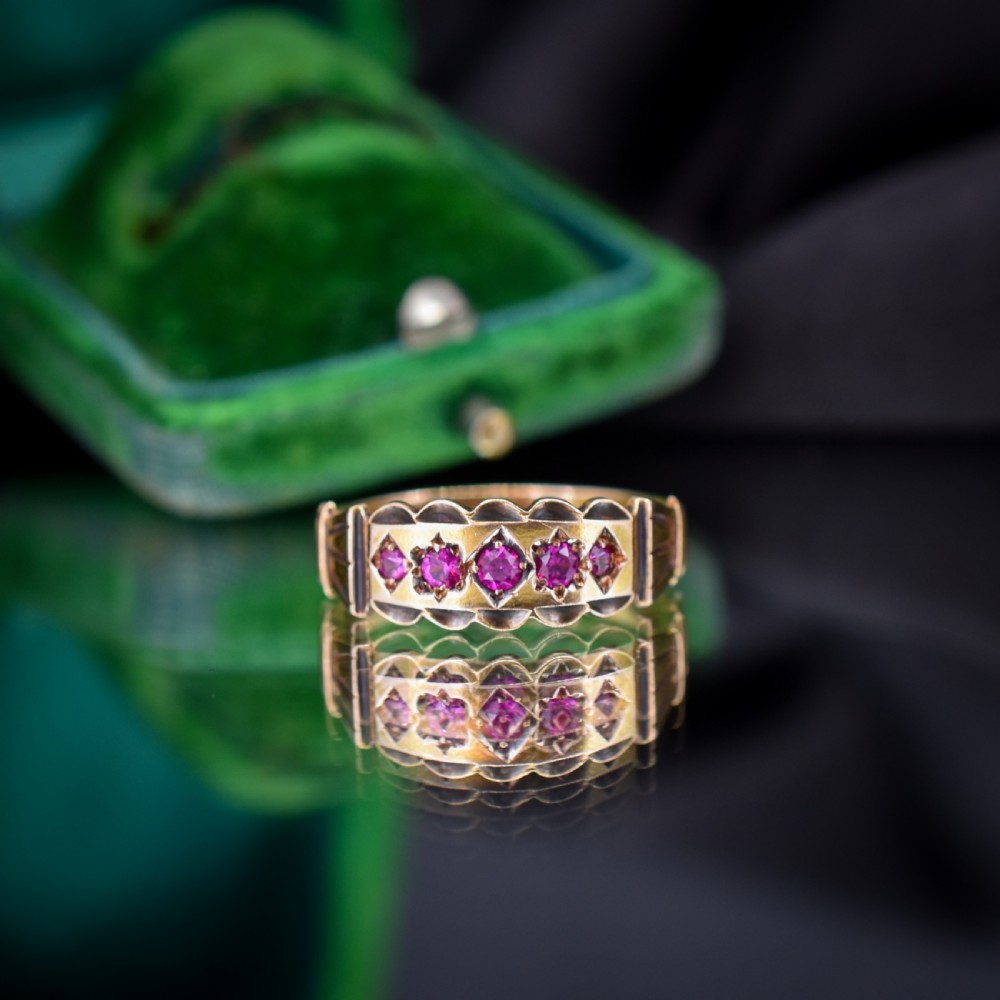An antique Victorian 15ct yellow gold band ring set with five red-pink rubies in star-engraved settings with a scalloped border. View III
