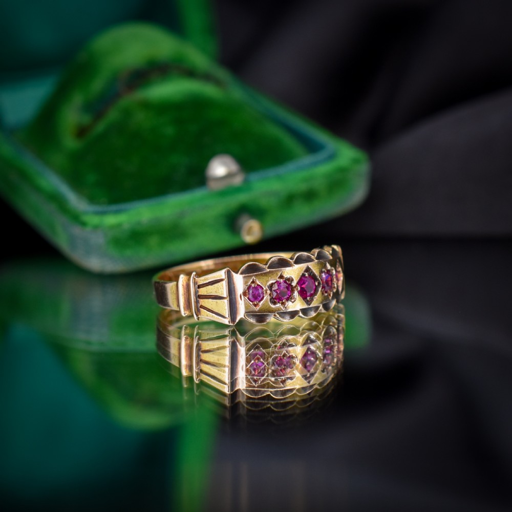 An antique Victorian 15ct yellow gold band ring set with five red-pink rubies in star-engraved settings with a scalloped border. View IV