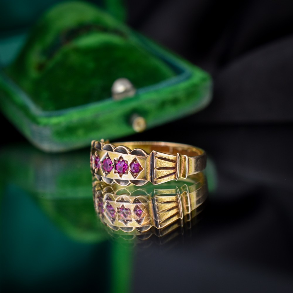 An antique Victorian 15ct yellow gold band ring set with five red-pink rubies in star-engraved settings with a scalloped border. View VI