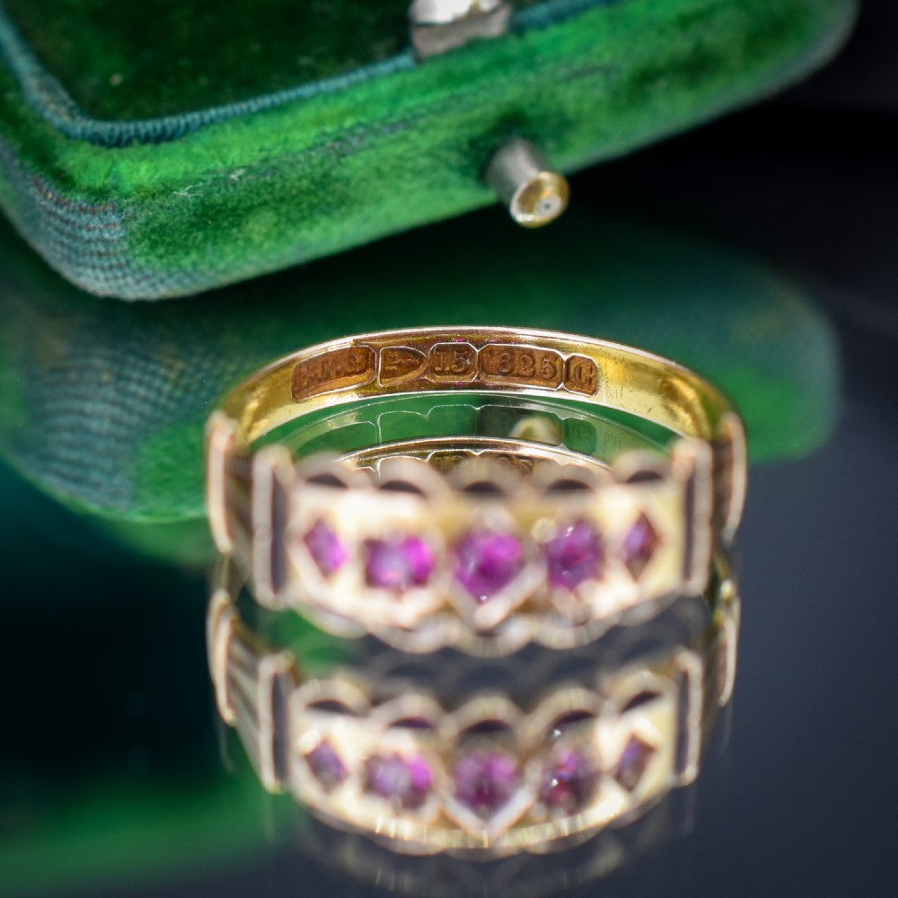 An antique Victorian 15ct yellow gold band ring set with five red-pink rubies in star-engraved settings with a scalloped border. View VII