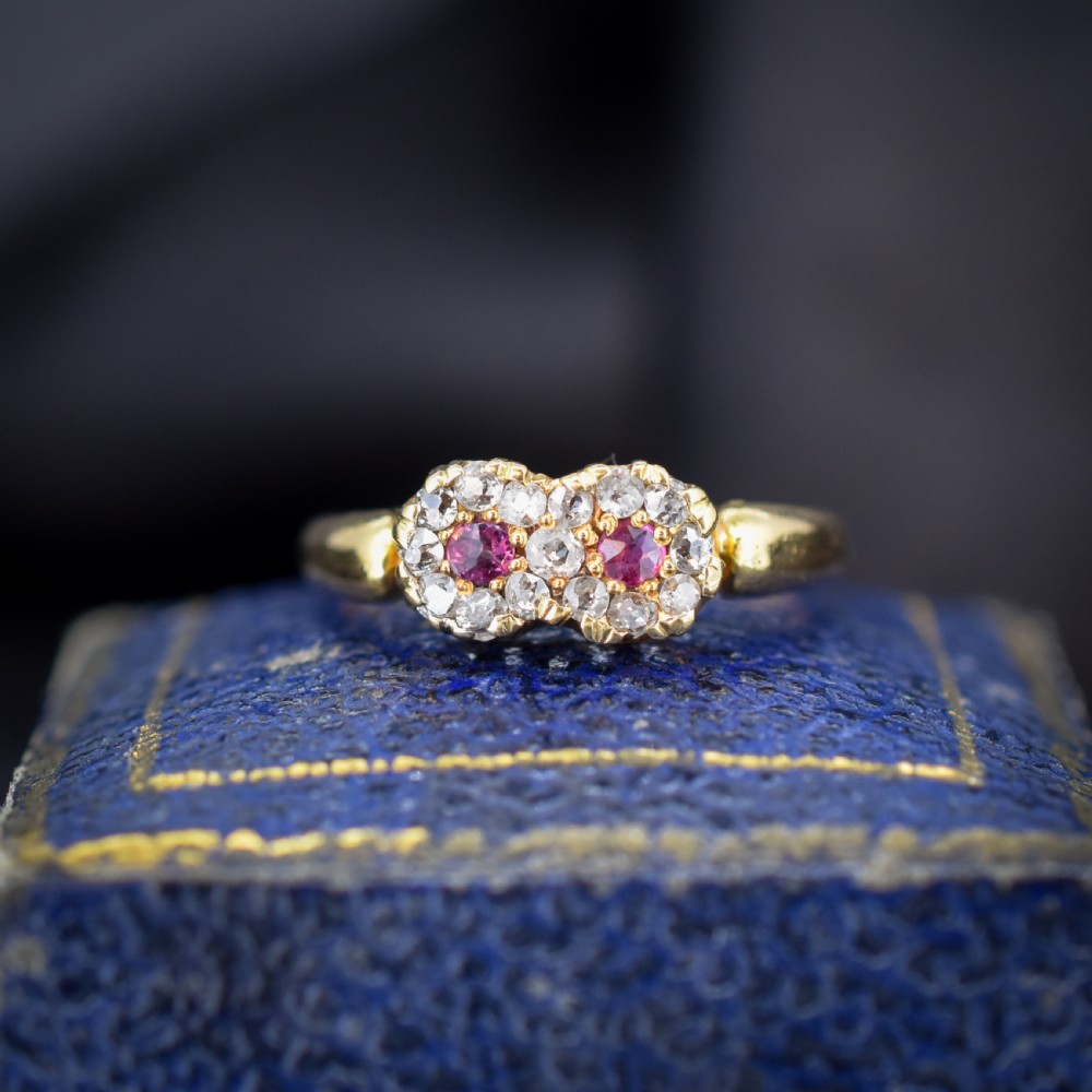 An antique 18ct yellow gold ring featuring a figure-of-eight double cluster set with two central pinkish-red rubies surrounded by small diamonds. View II