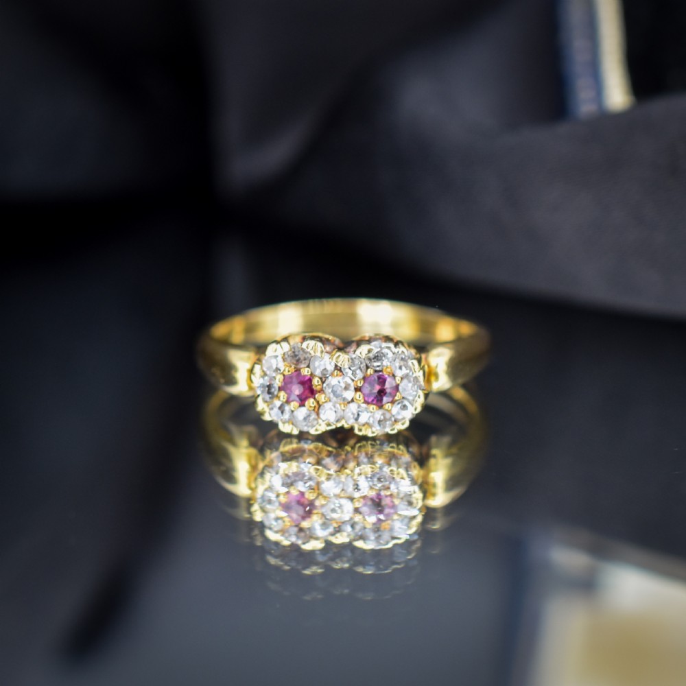 An antique 18ct yellow gold ring featuring a figure-of-eight double cluster set with two central pinkish-red rubies surrounded by small diamonds. View IV