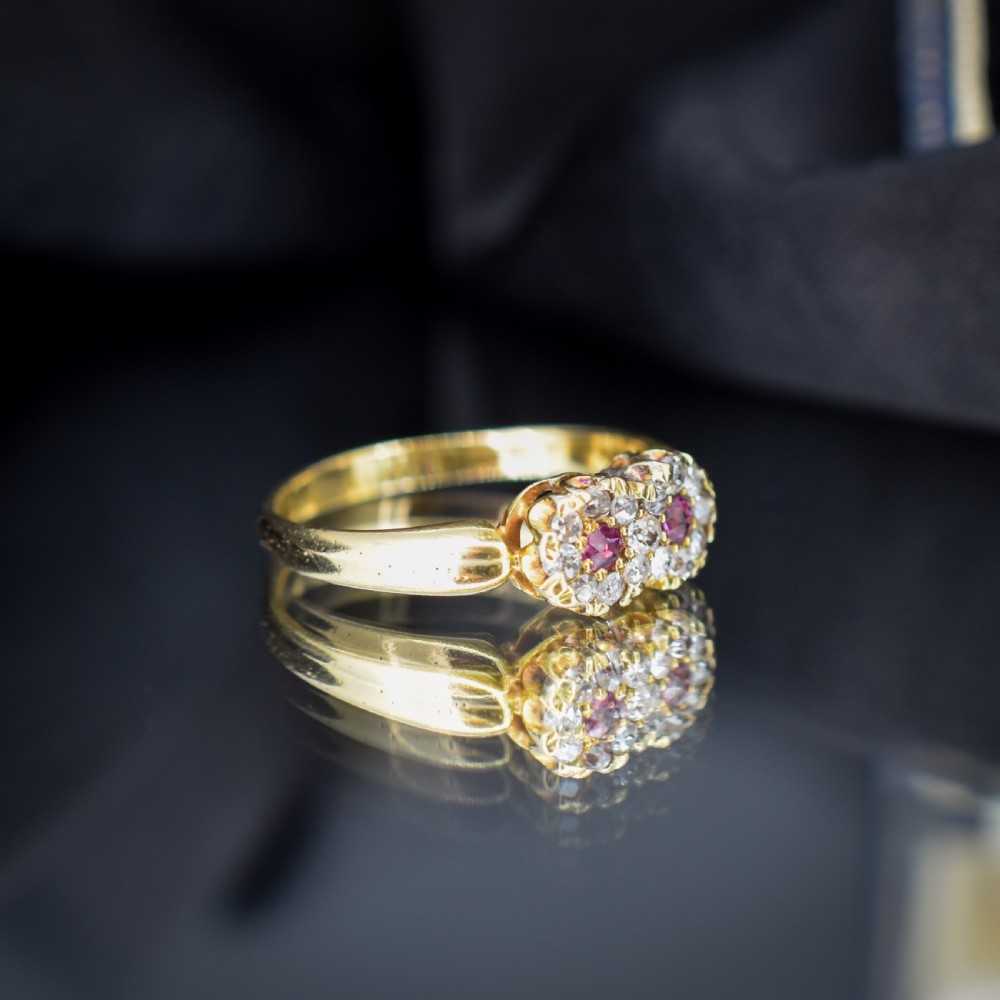 An antique 18ct yellow gold ring featuring a figure-of-eight double cluster set with two central pinkish-red rubies surrounded by small diamonds. View V