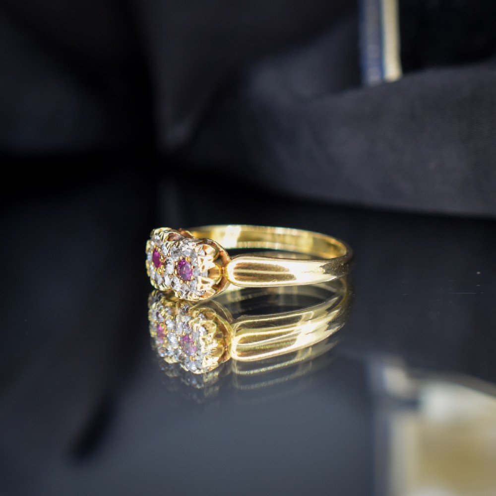 An antique 18ct yellow gold ring featuring a figure-of-eight double cluster set with two central pinkish-red rubies surrounded by small diamonds. View VII