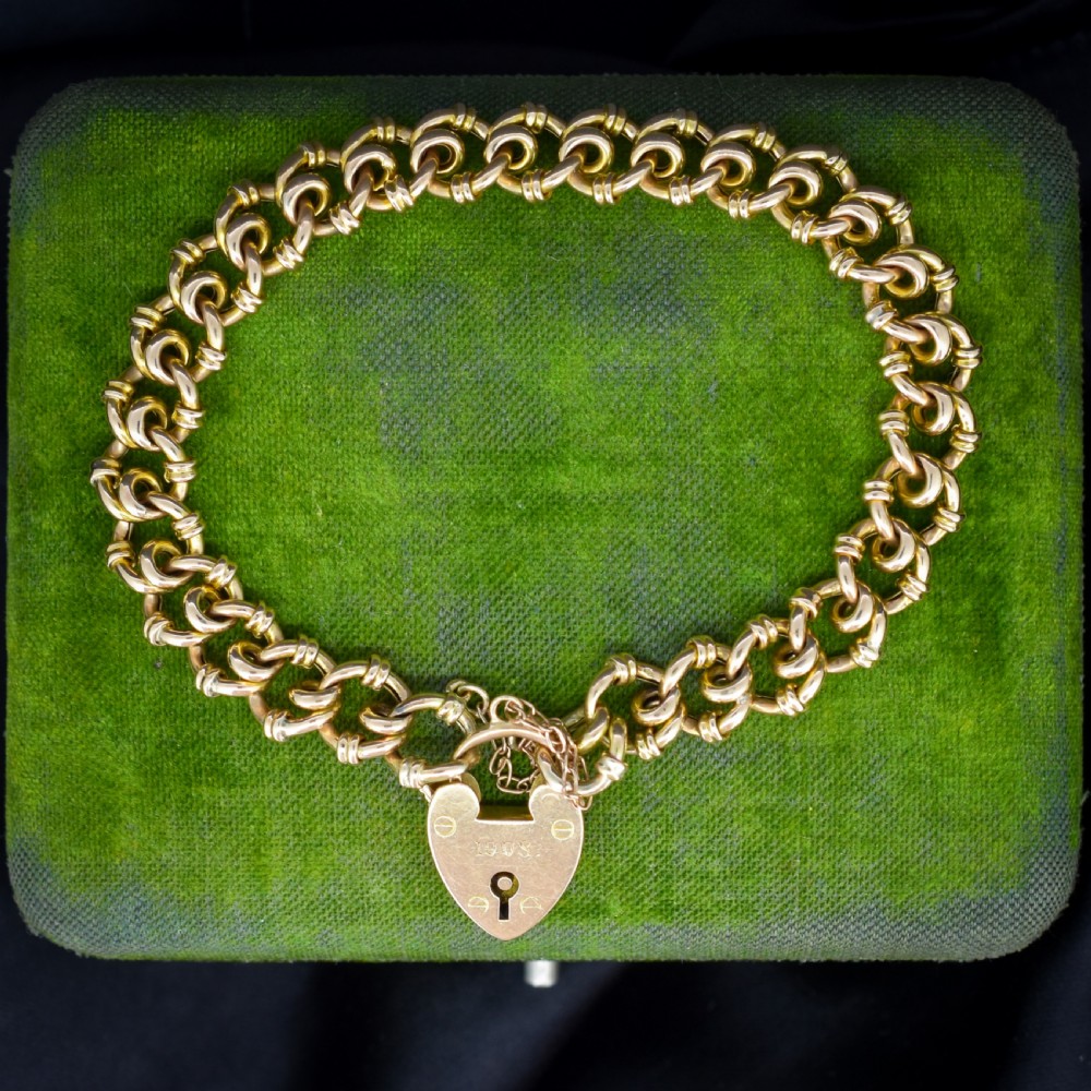 An antique 15ct yellow gold gate link bracelet fitted with an engraved heart padlock clasp and a safety chain.