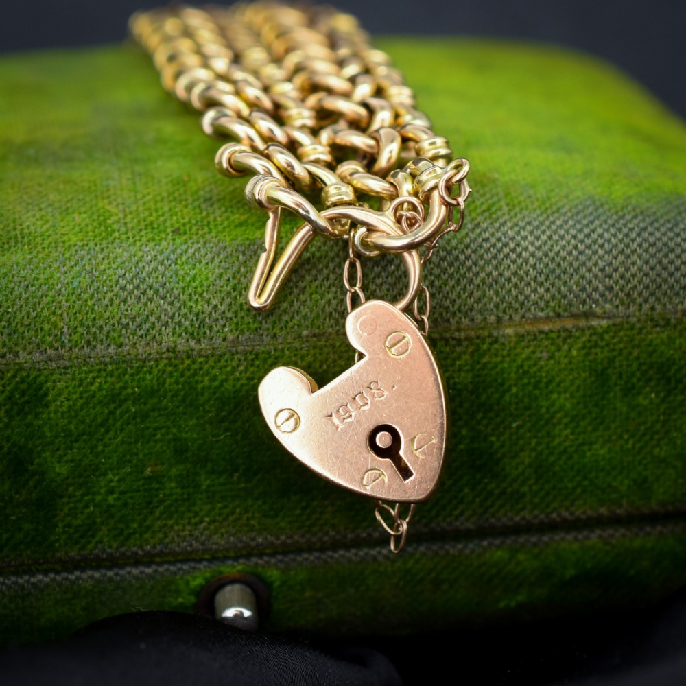 An antique 15ct yellow gold gate link bracelet fitted with an engraved heart padlock clasp and a safety chain. View IV