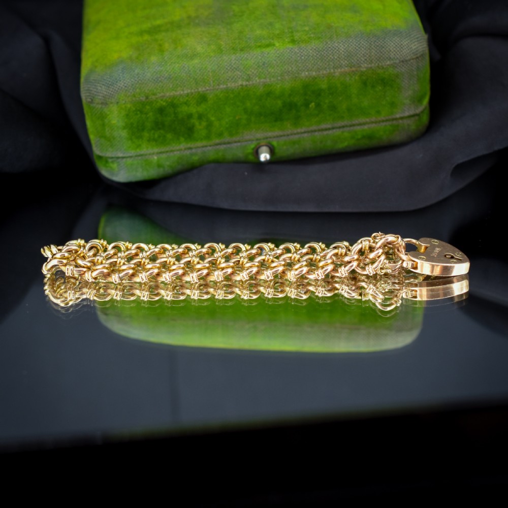 An antique 15ct yellow gold gate link bracelet fitted with an engraved heart padlock clasp and a safety chain. View V