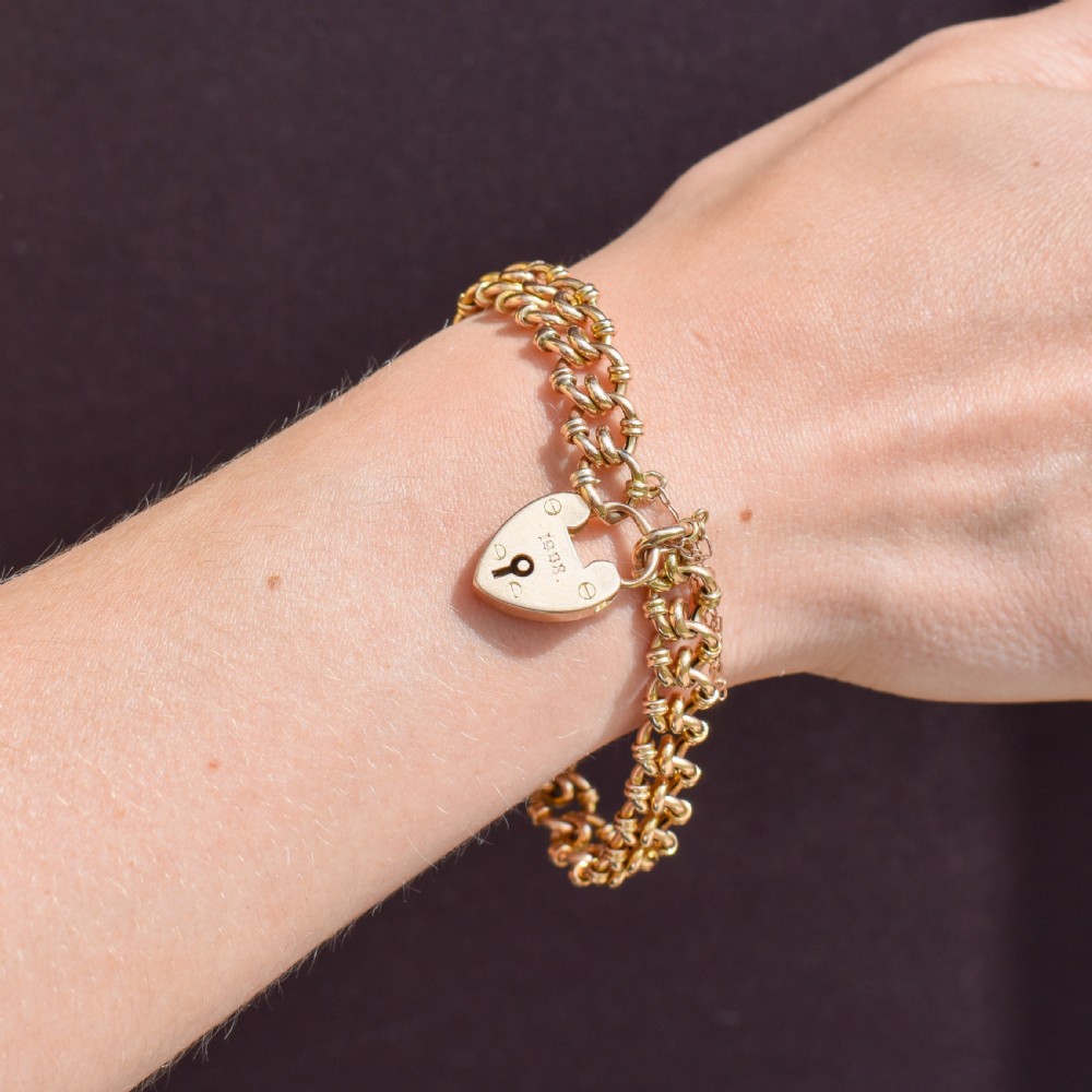 An antique 15ct yellow gold gate link bracelet fitted with an engraved heart padlock clasp and a safety chain. View VIII