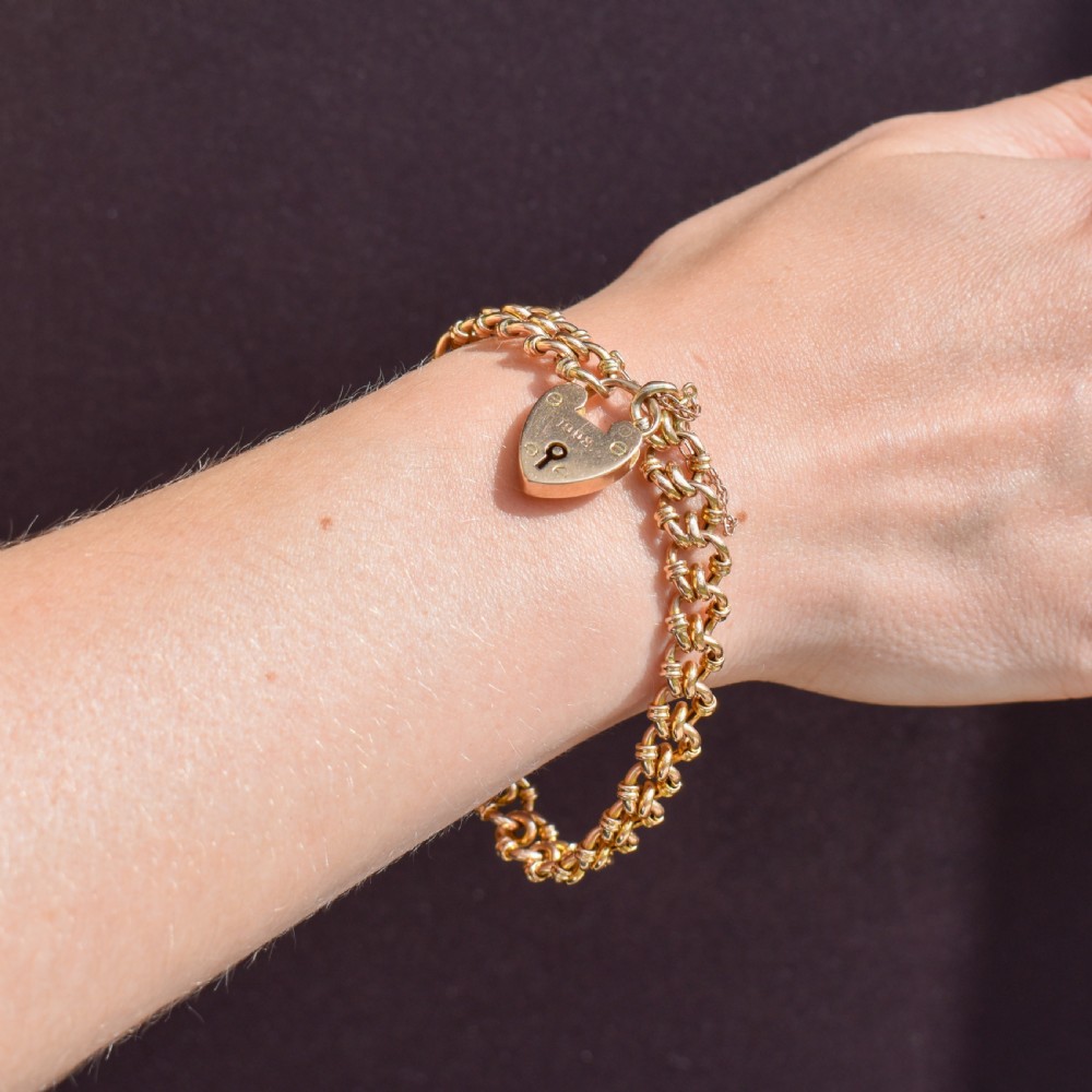 An antique 15ct yellow gold gate link bracelet fitted with an engraved heart padlock clasp and a safety chain. View IX