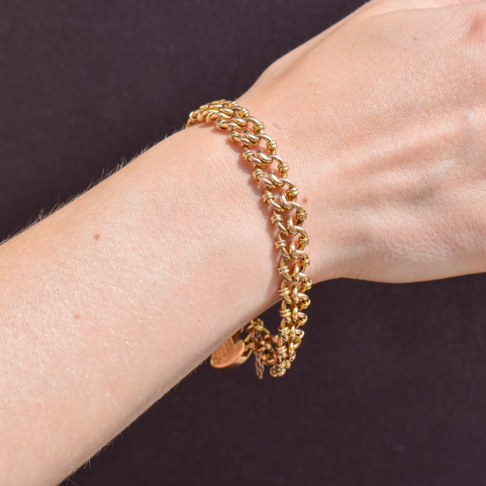 An antique 15ct yellow gold gate link bracelet fitted with an engraved heart padlock clasp and a safety chain. View X