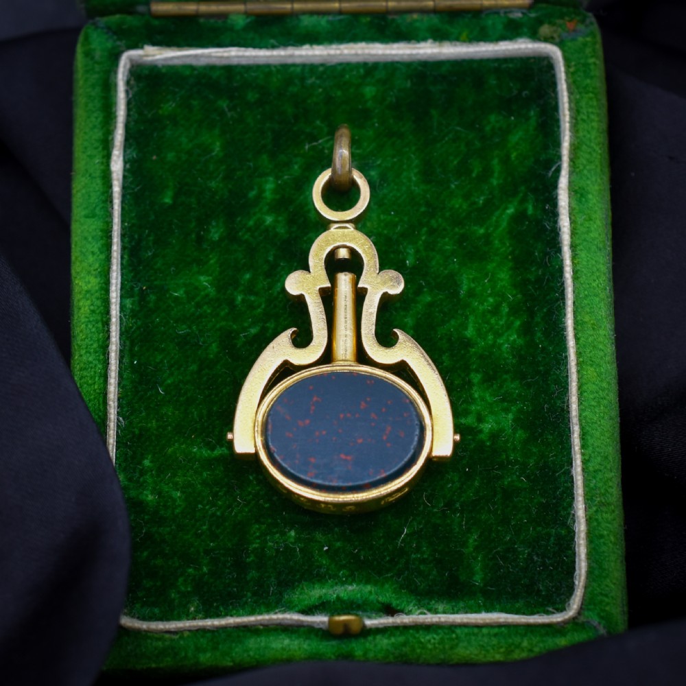 An antique Victorian 18ct gold spinning fob watch key pendant featuring a swivel-set oval dark green bloodstone with red flecks held within a scrolled mount.