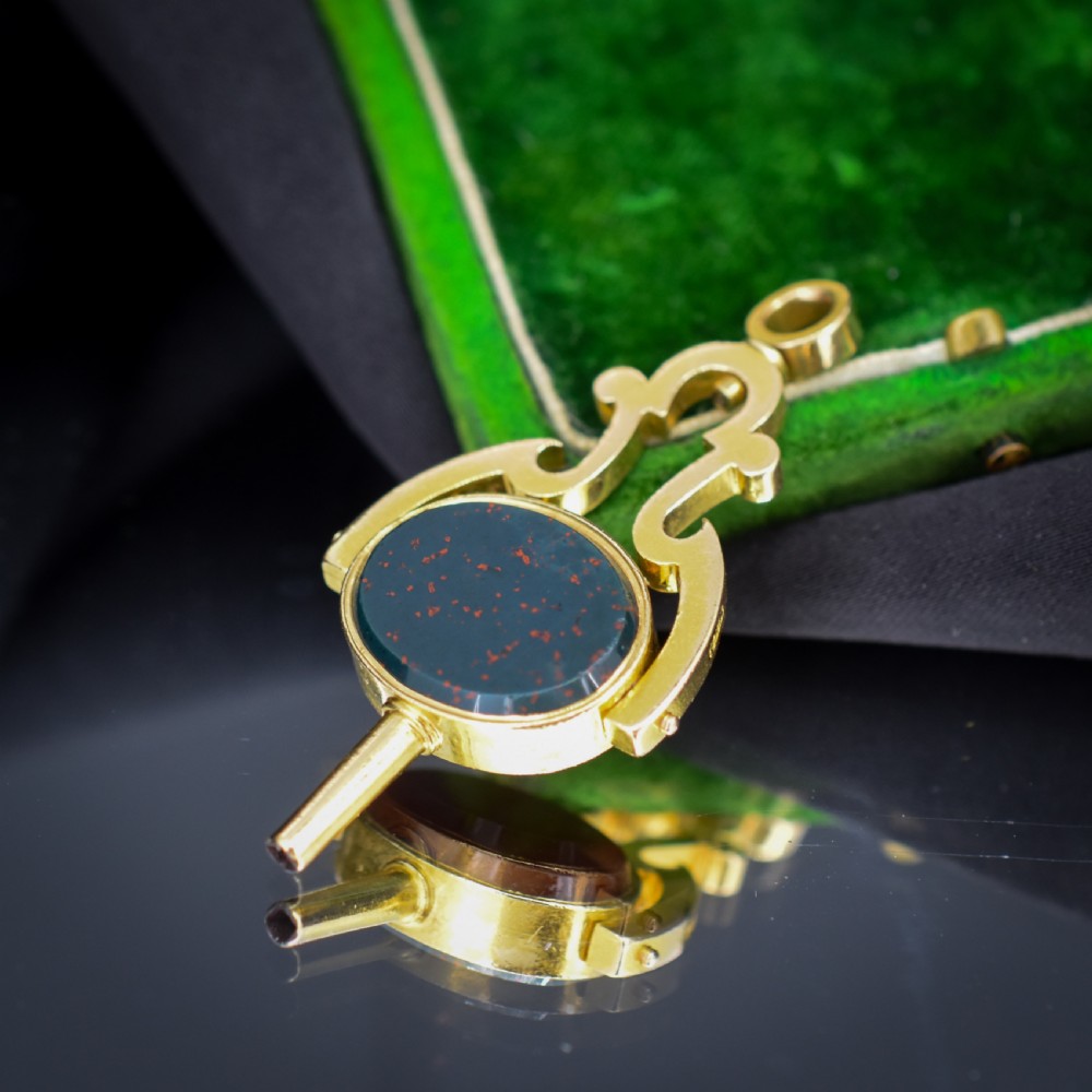 An antique Victorian 18ct gold spinning fob watch key pendant featuring a swivel-set oval dark green bloodstone with red flecks held within a scrolled mount. View VII