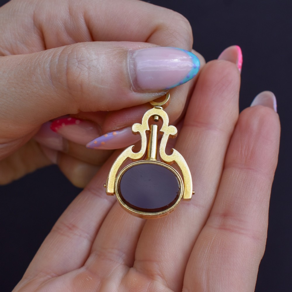 An antique Victorian 18ct gold spinning fob watch key pendant featuring a swivel-set oval dark green bloodstone with red flecks held within a scrolled mount. View IX