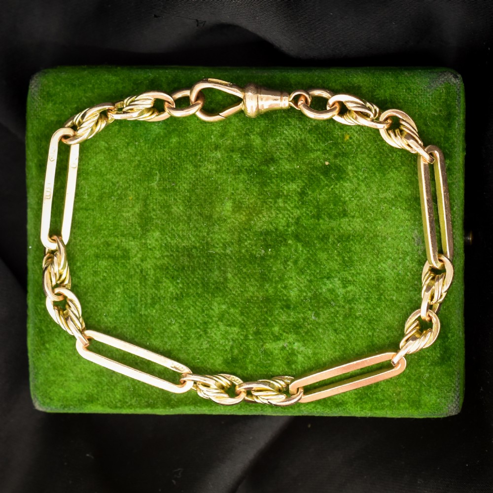 An antique 9ct yellow gold link bracelet composed of alternating trombone links and twisted love knots with a dog clip clasp.