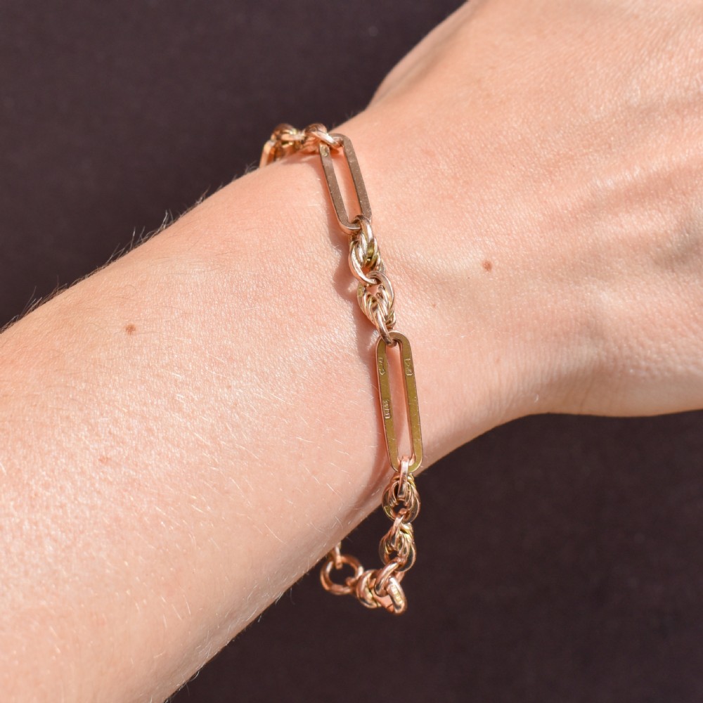 An antique 9ct yellow gold link bracelet composed of alternating trombone links and twisted love knots with a dog clip clasp. View III