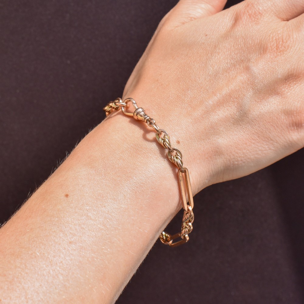 An antique 9ct yellow gold link bracelet composed of alternating trombone links and twisted love knots with a dog clip clasp. View IV