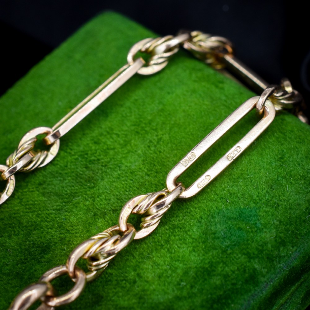 An antique 9ct yellow gold link bracelet composed of alternating trombone links and twisted love knots with a dog clip clasp. View VII