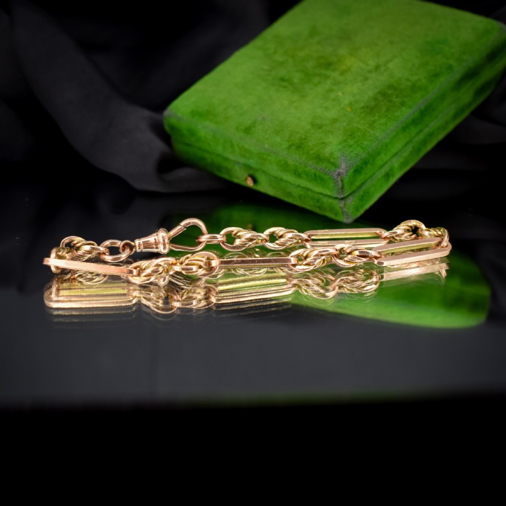 An antique 9ct yellow gold link bracelet composed of alternating trombone links and twisted love knots with a dog clip clasp. View IX