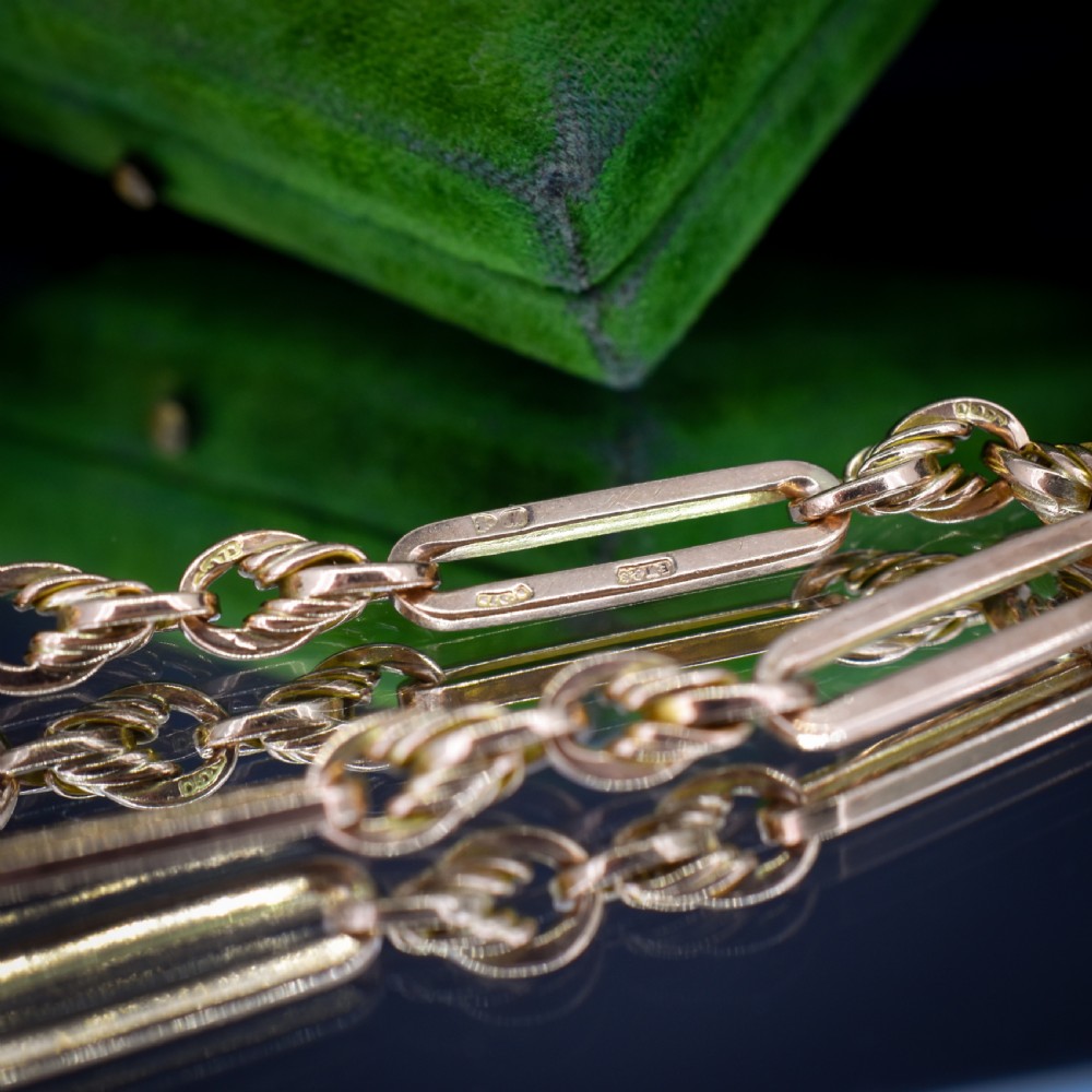 An antique 9ct yellow gold link bracelet composed of alternating trombone links and twisted love knots with a dog clip clasp. View X