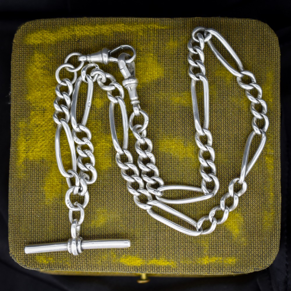 An antique sterling silver double Albert watch chain featuring Figaro style links, a central T-bar, and dual swivel clasps.