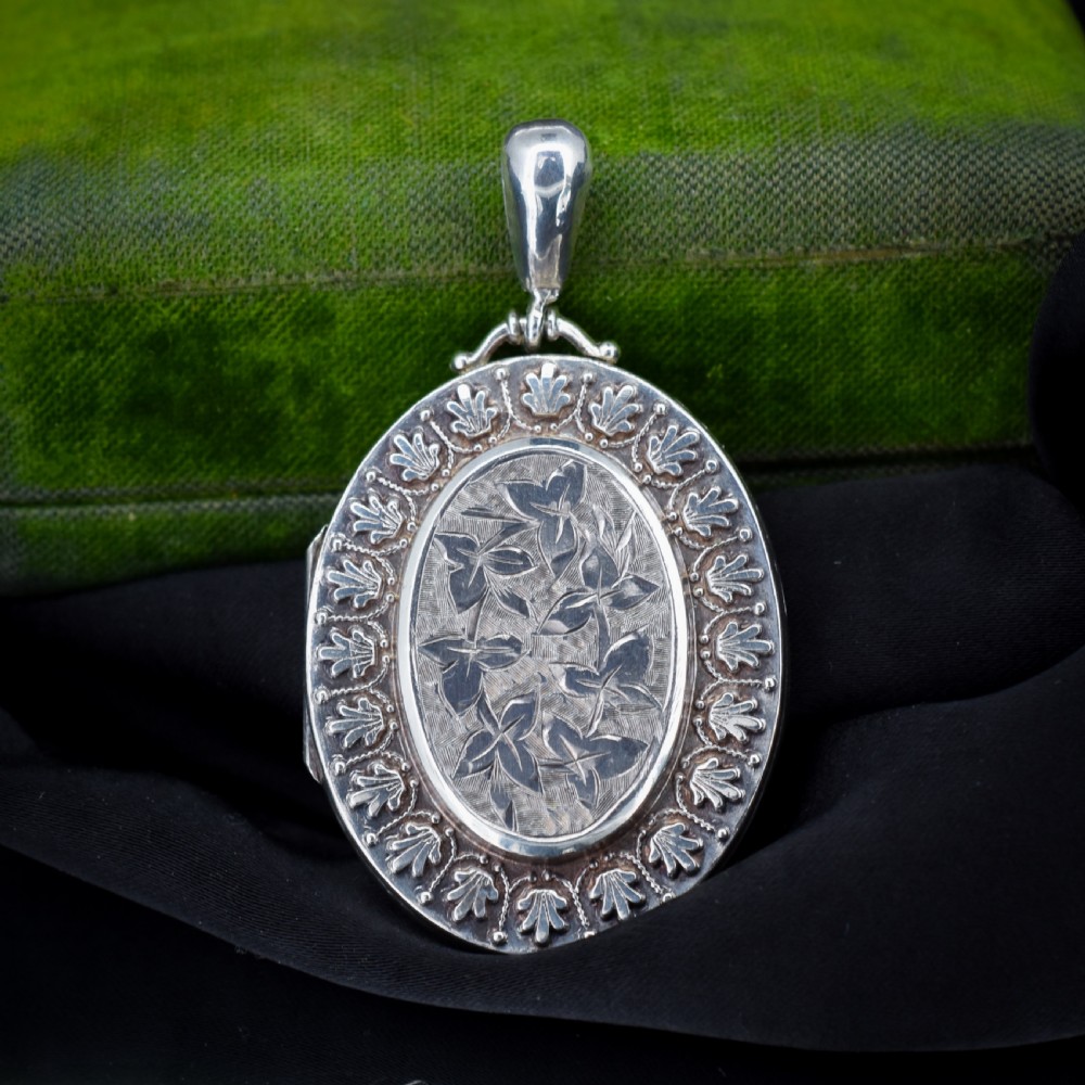 A Victorian oval sterling silver photo locket featuring a central hand-engraved ivy leaf motif framed by an anthemion border. View II