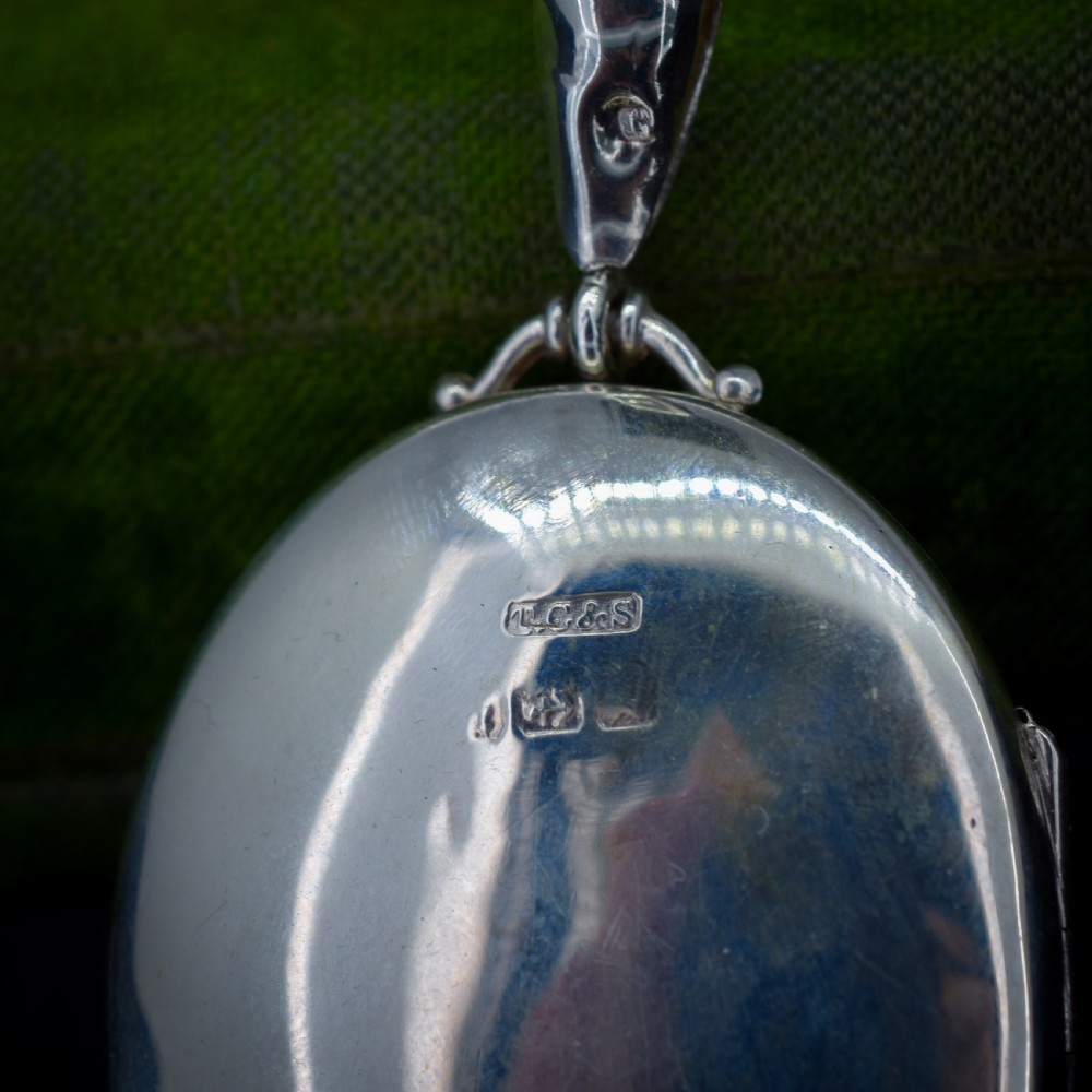 A Victorian oval sterling silver photo locket featuring a central hand-engraved ivy leaf motif framed by an anthemion border. View IV