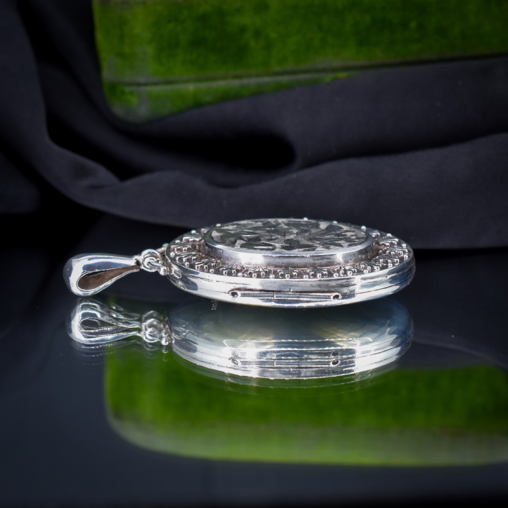 A Victorian oval sterling silver photo locket featuring a central hand-engraved ivy leaf motif framed by an anthemion border. View VI