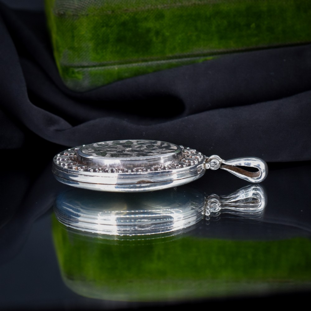 A Victorian oval sterling silver photo locket featuring a central hand-engraved ivy leaf motif framed by an anthemion border. View VII