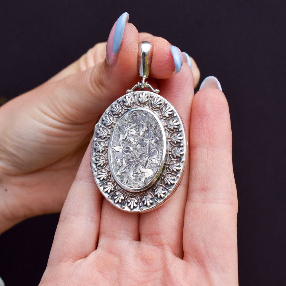 A Victorian oval sterling silver photo locket featuring a central hand-engraved ivy leaf motif framed by an anthemion border. View VIII