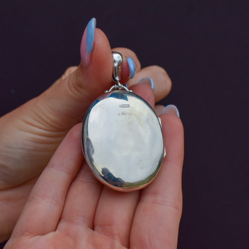 A Victorian oval sterling silver photo locket featuring a central hand-engraved ivy leaf motif framed by an anthemion border. View IX